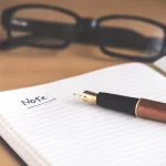 Penna stilografica marrone sul taccuino con scritto Note