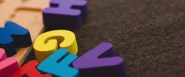 Lettere colorate sopra una tavola di legno di un gioco per imparare l’alfabeto