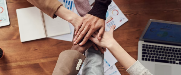 Colleghi che appoggiano le loro mani una sopra l'altra, in segno di lavoro di squadra
